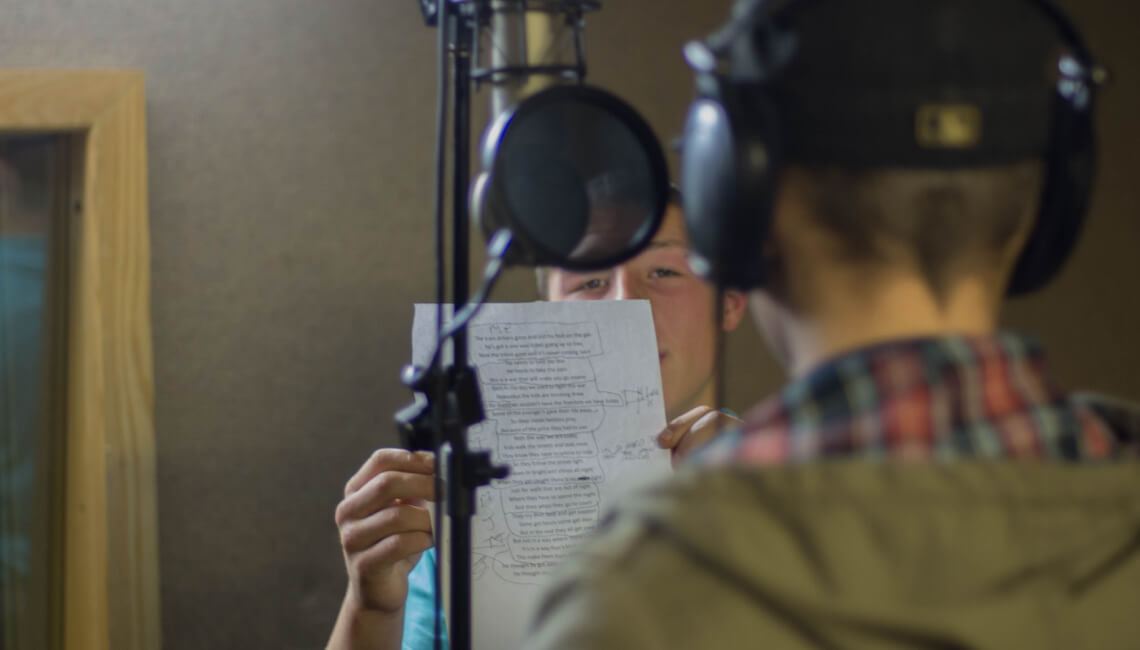 A young adult reading lines in a recording studio