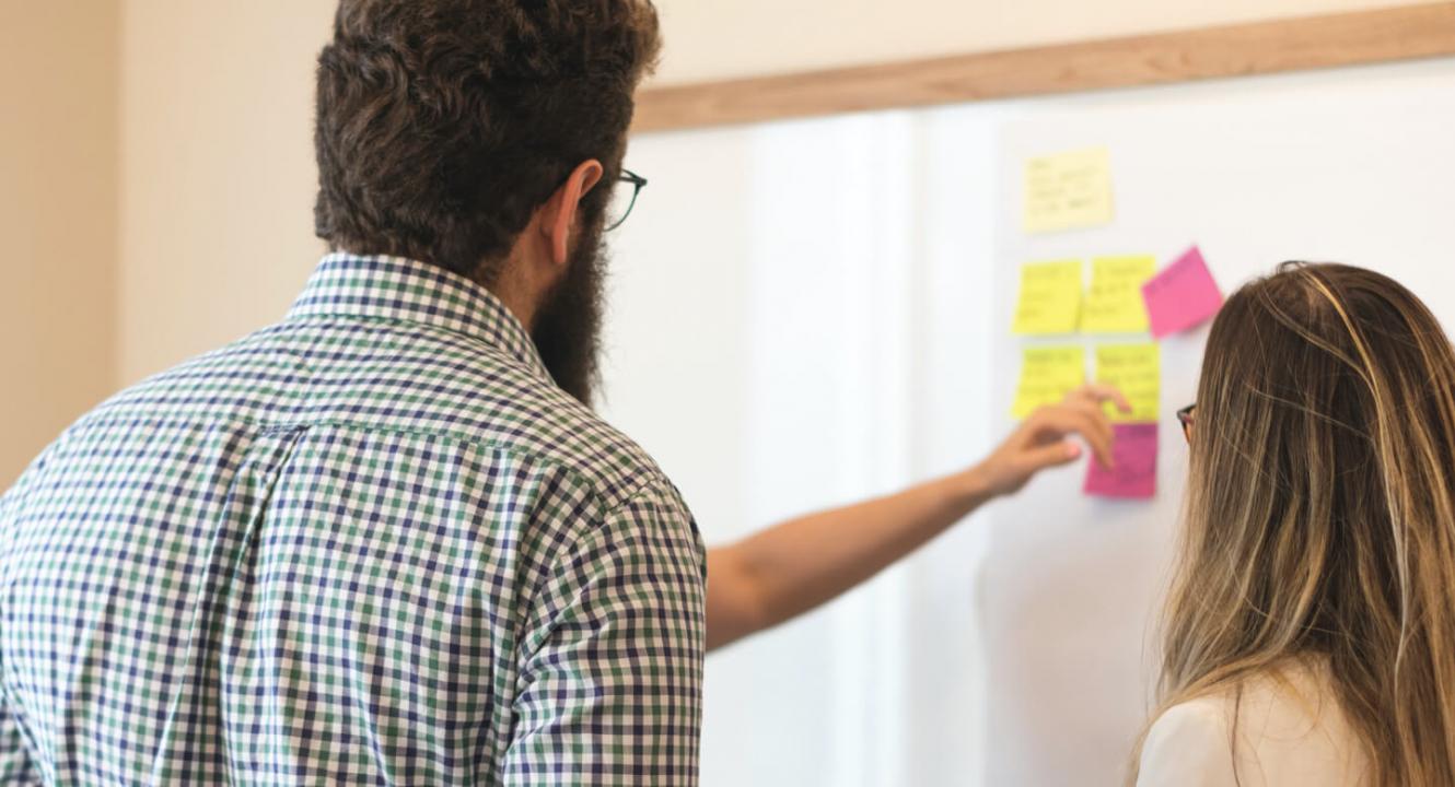 Group of people using a white board to discuss ideas
